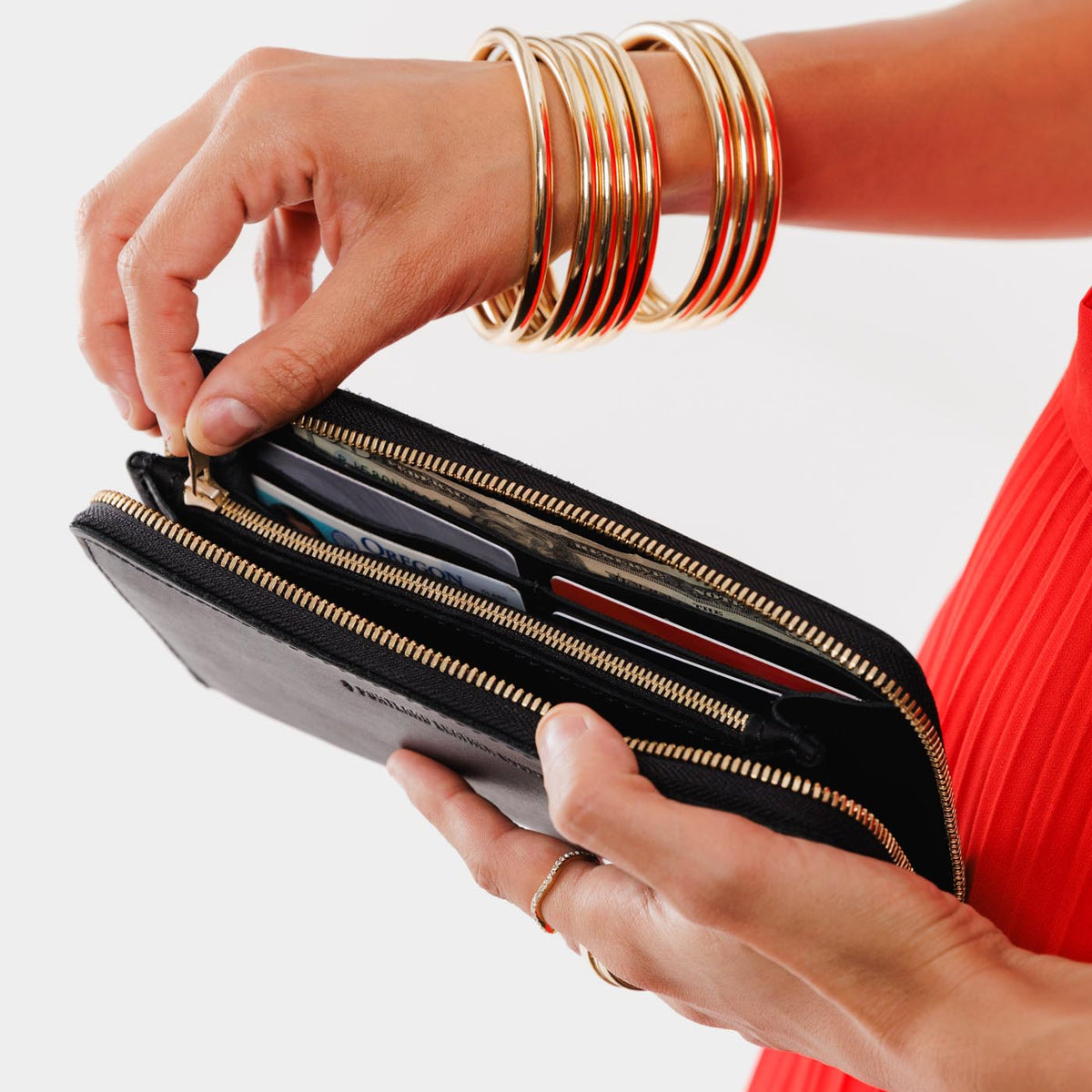 Black | Model holding large accordion leather wallet with zipper open
