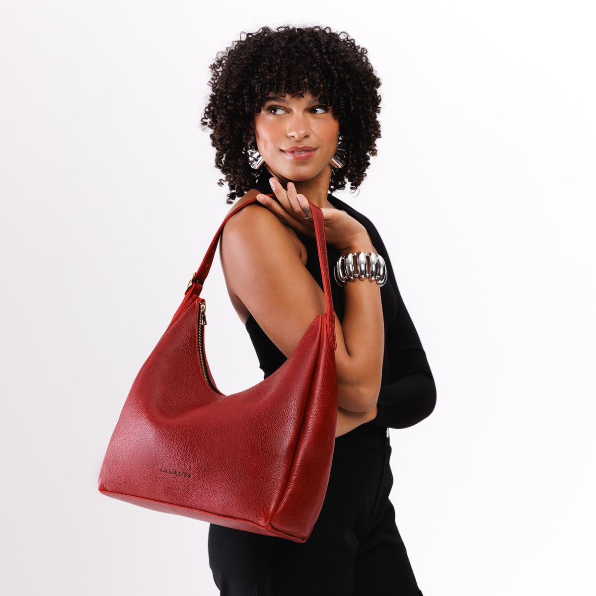 Chili Red*Large | Model holding u-shaped, flat-bottomed leather shoulder bag with adjustable strap