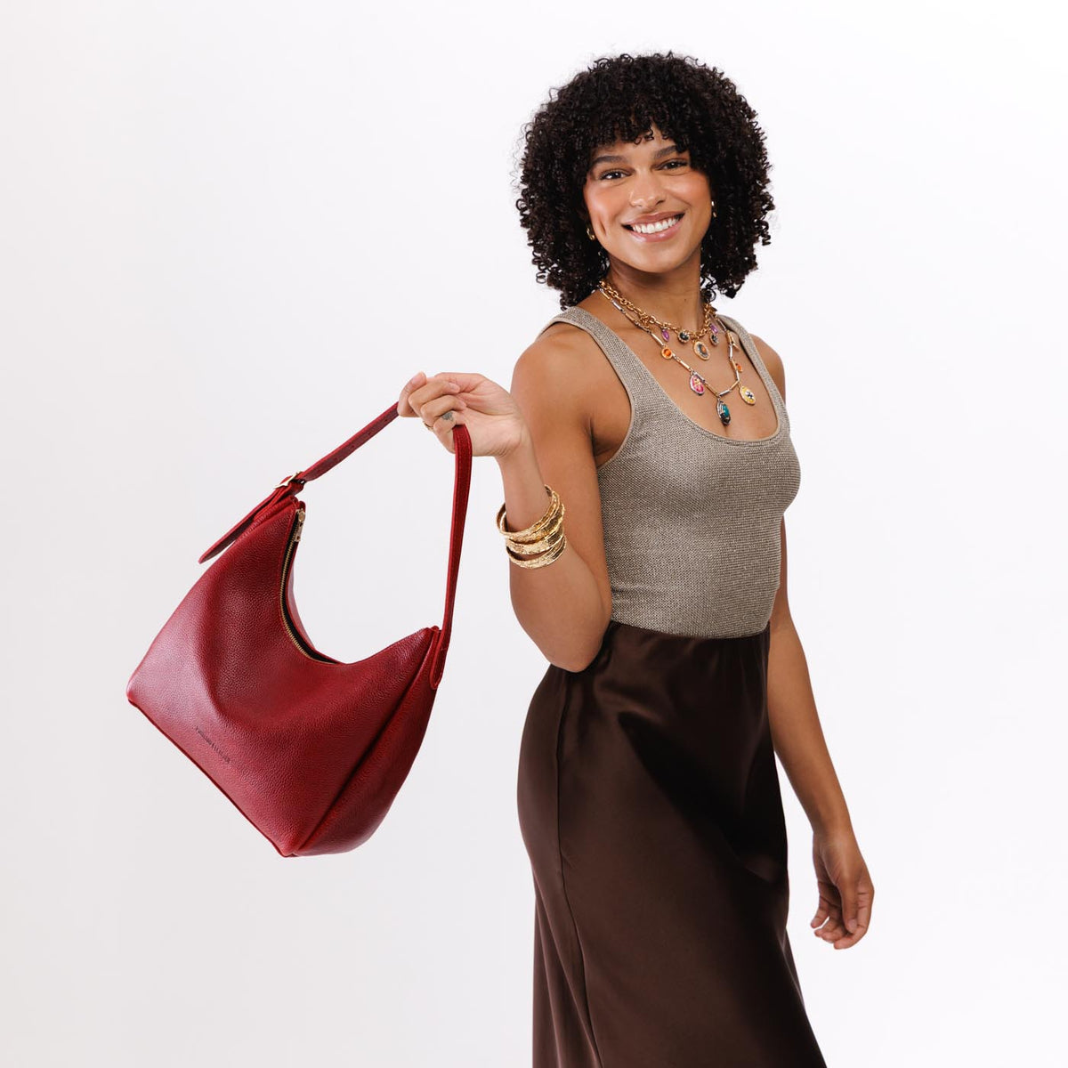 Chili Red*Medium | Model holding u-shaped, flat-bottomed leather shoulder bag with adjustable strap