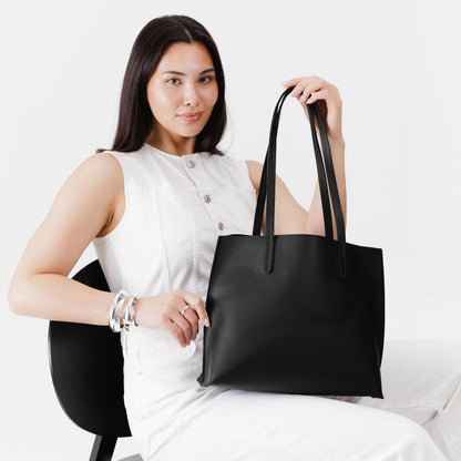 Black*Medium | Model holding leather tote bag with interior snap key loop