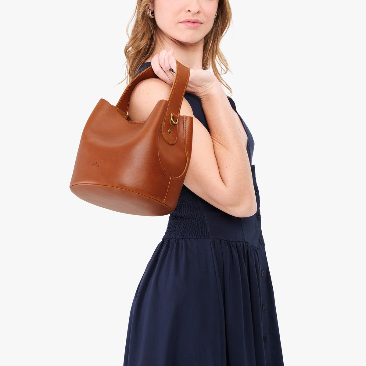 Honey*Small | Model holding symmetrical bucket bag with handle, latch closure, and removable crossbody strap