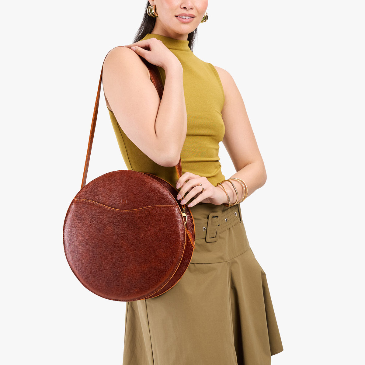 Nutmeg | Model carrying large circle shaped leather bag with top zipper and carrying strap