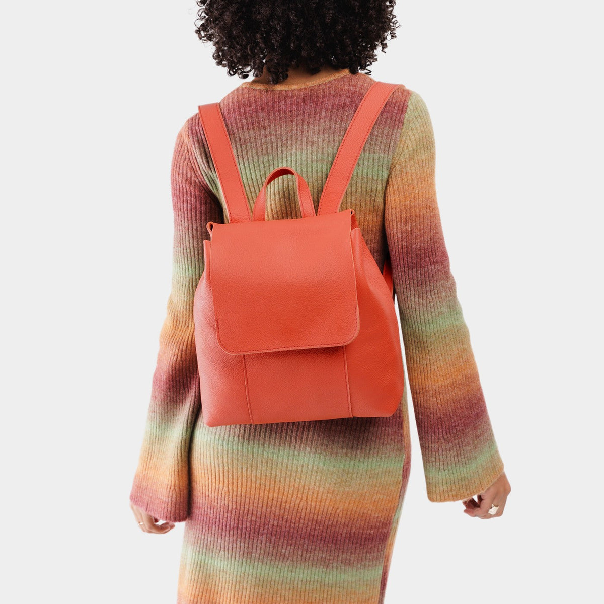 Coral | Model wearing a leather backpack on a white background