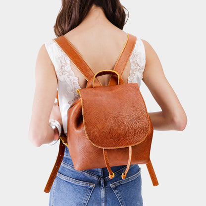 Sienna | Pebbled leather drawstring backpack being worn by a person.