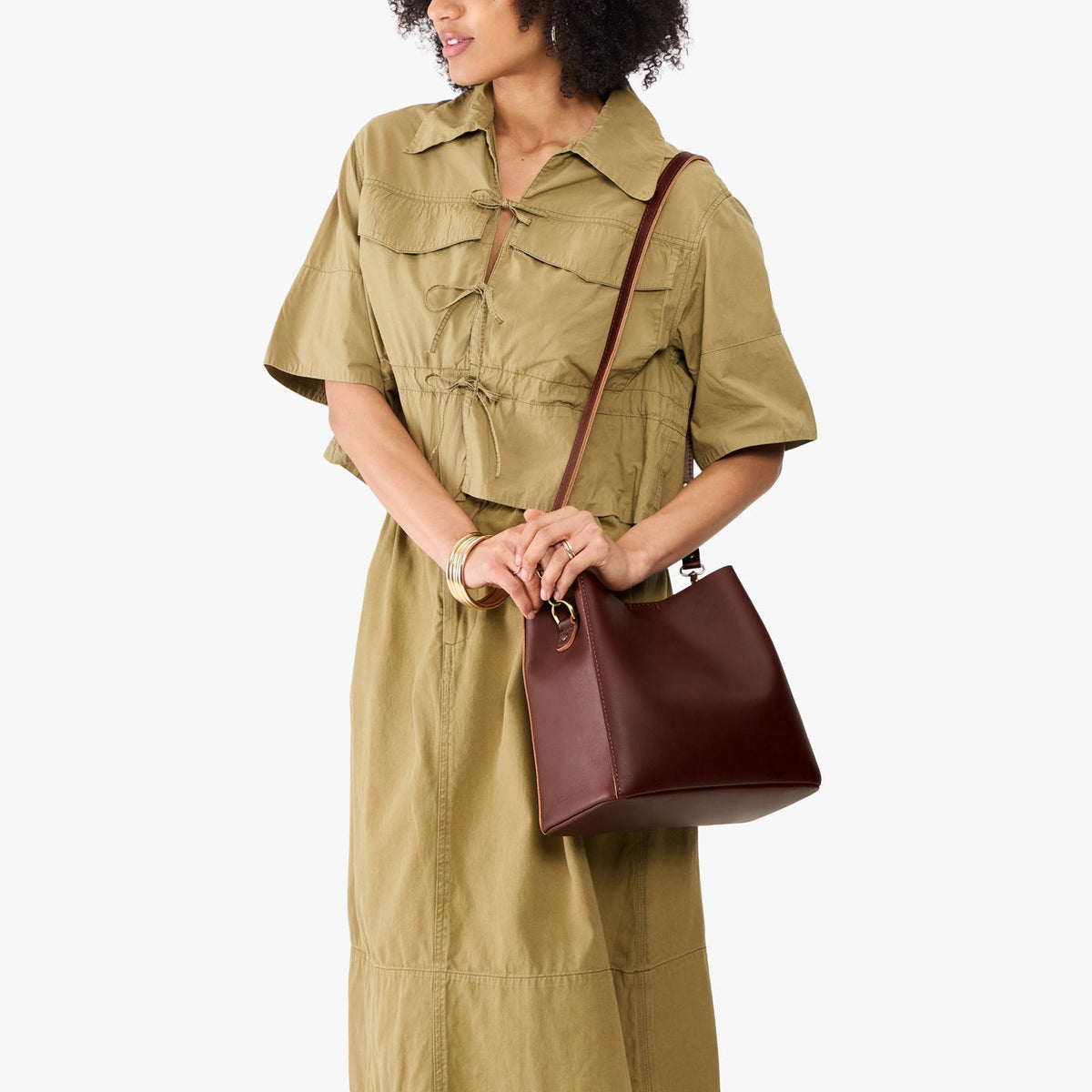 Cognac | Model wearing symmetrical bucket bag with latch closure and removable crossbody strap