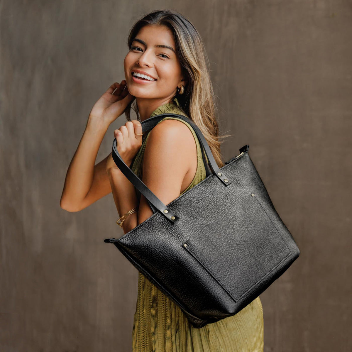 Pebbled--black*Zipper | Model holding large zipper leather tote bag with sturdy bridle handles and front pocket