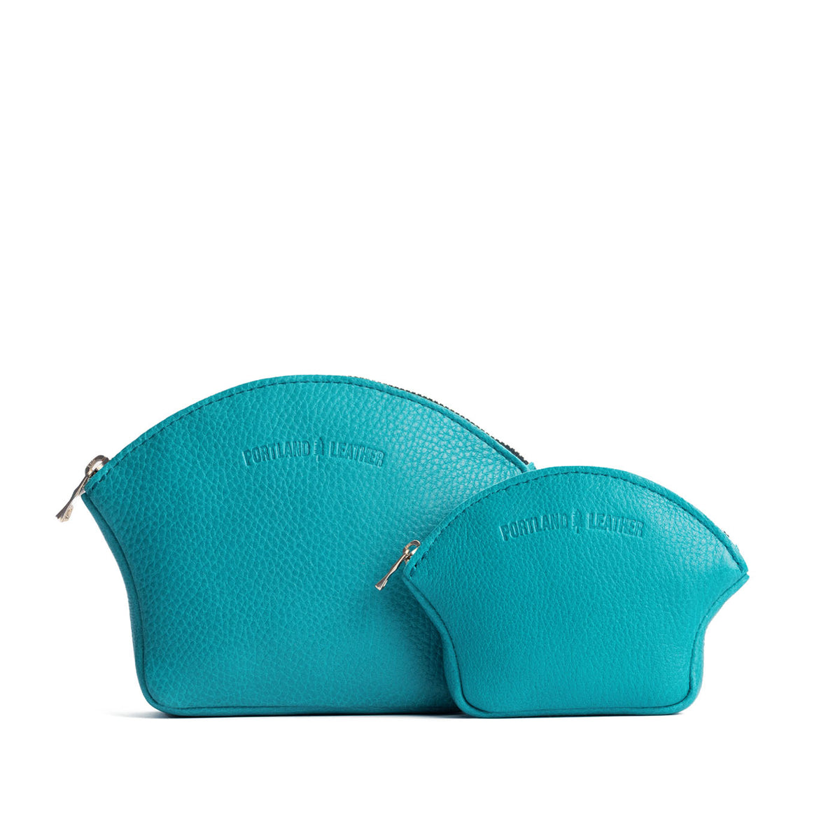 Baja | Comparison shot of small and large seashell shaped leather makeup bags with curved top zipper and flat bottom