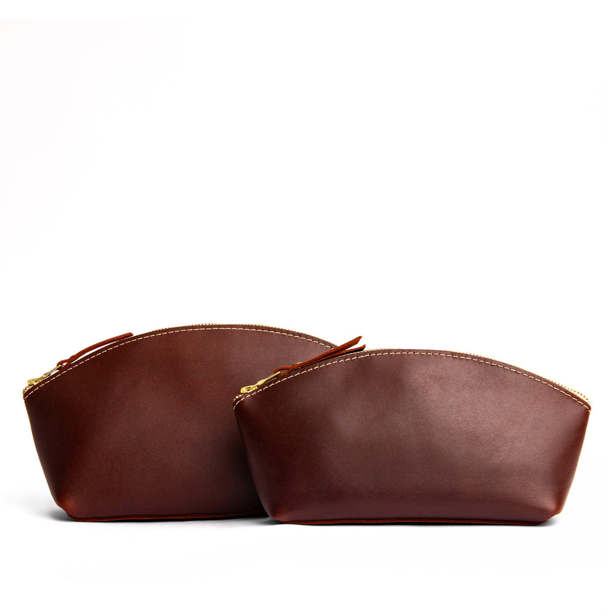 Cognac | Size comparison shot of two spacious leather makeup bags with curved seams and top zipper