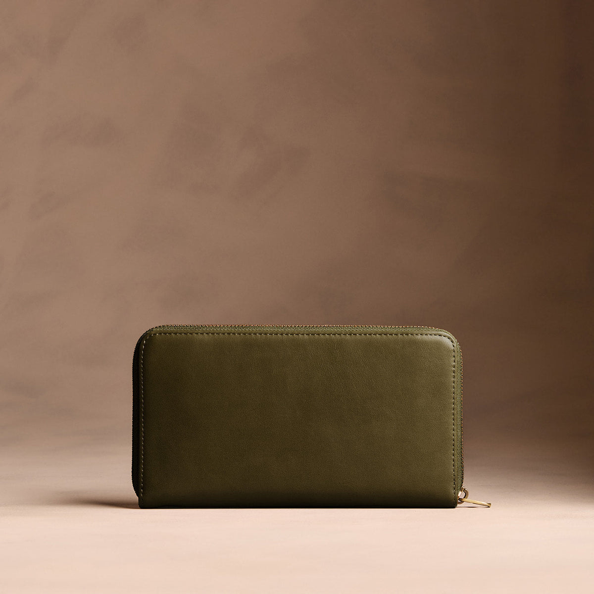 Bay Green | Full zip around wallet with a strap on a brown background