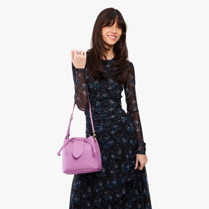 Calla Lily*Small | Model holding symmetrical leather bag with leather drawstring closure and adjustable shoulder strap