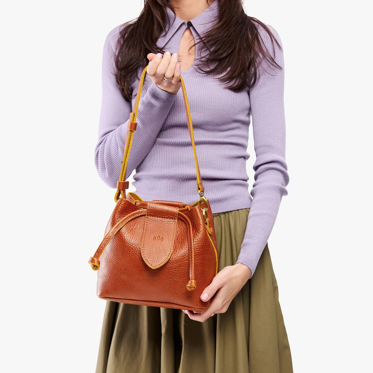 Sienna*Small | Model holding symmetrical leather bag with leather drawstring closure and adjustable shoulder strap