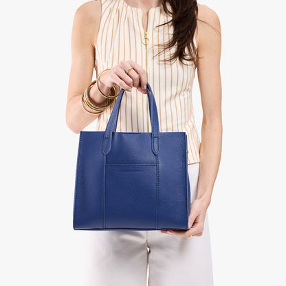 Molino Blue | Model holding structured mid-size tote bag with overlapping panels and crossbody strap