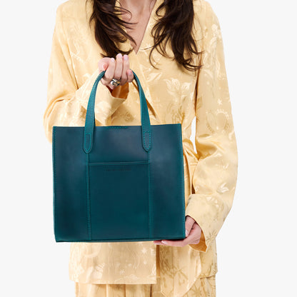 Westward Blue | Model holding structured mid-size tote bag with overlapping panels and crossbody strap