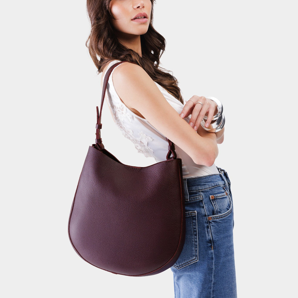 Plum*Large | Woman wearing rounded shoulder bag with adjustable strap on a white background