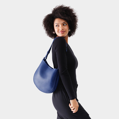 Molino Blue*Medium | Woman wearing rounded shoulder bag with adjustable strap on a white background