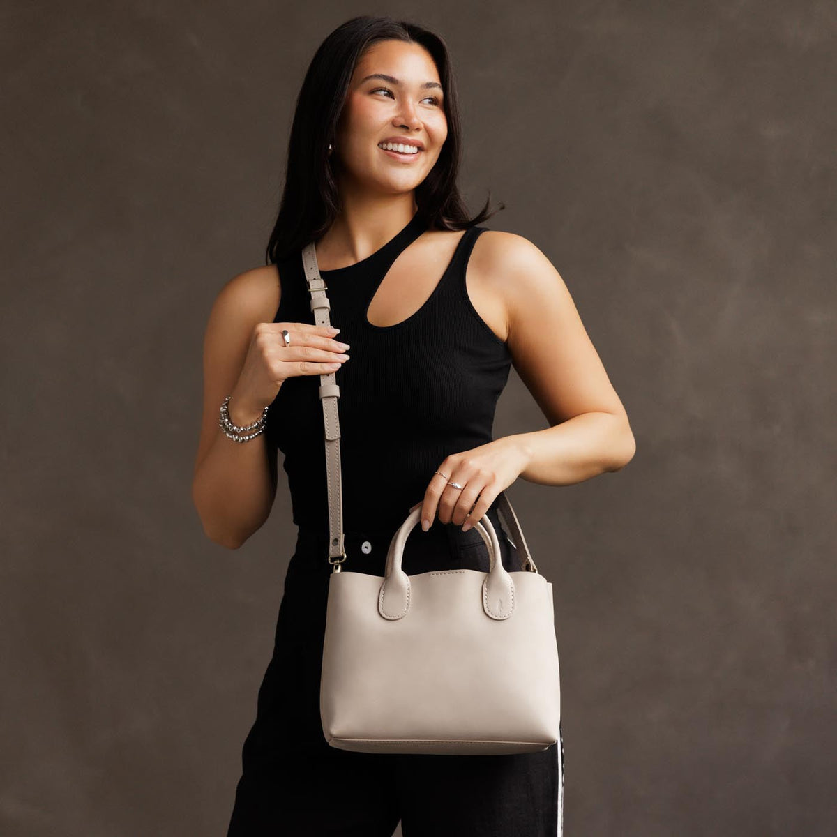 Dragon Bone*Large | Model holding mid-size tote purse with structured leather handles and crossbody strap