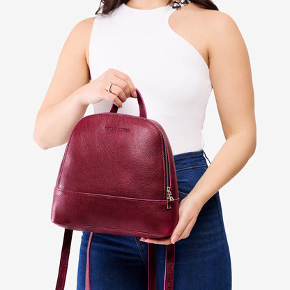Orchid | Model holding leather backpack with debossed Portland Leather logo on front