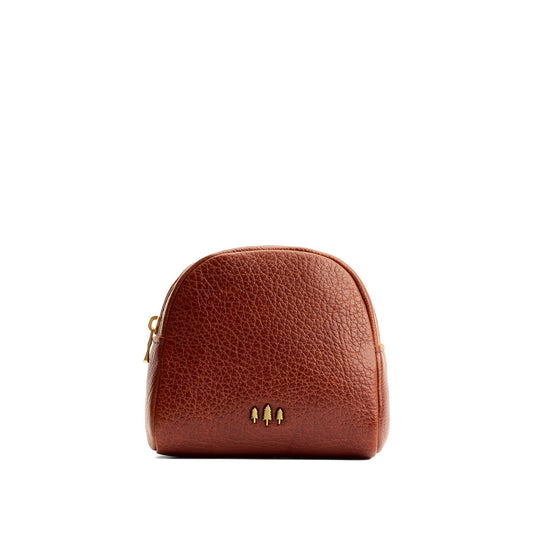 Nutmeg | Curved top leather pouch with zipper opening, flat base, and three metal tree emblems in front